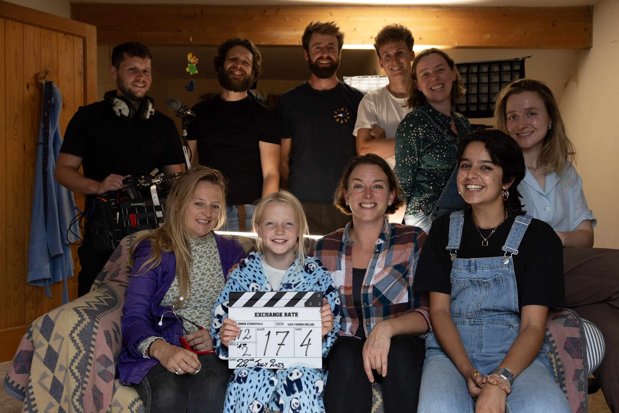 Cast and crew of Exchange Rate sitting together on the sofa of the film set.